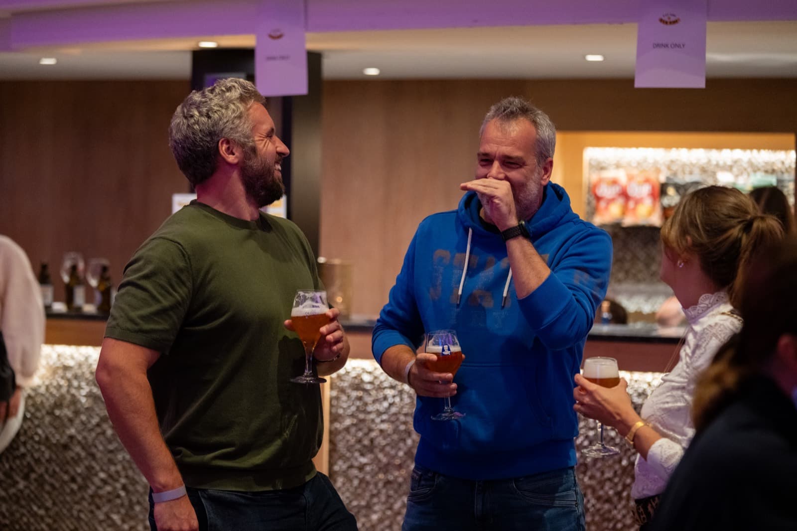 Des spectateurs rient au bar, un verre de bière à la main Il est temps d'en rire. Photo de la saison d'hiver